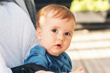 Outdoor close up portrait of adorable redheaded baby boy sitting in a buggy