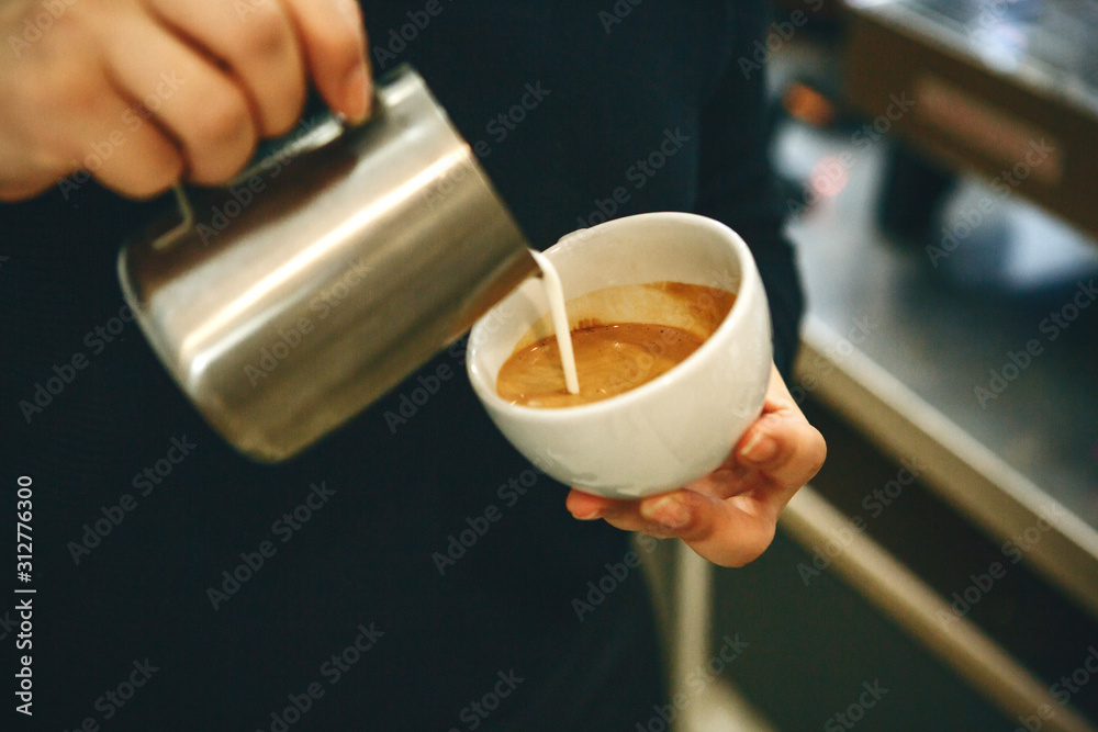 Barista pours milk or cream into coffee - obrazy, fototapety, plakaty 