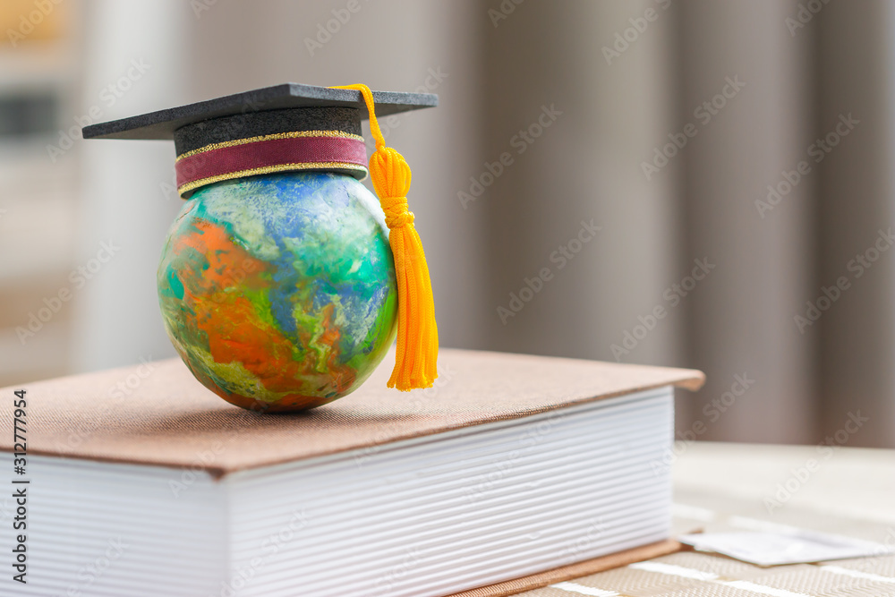 Education to learn study in world. Graduated student studying abroad international idea. Master degree hat on top globe book. Concept of graduate educational for long distane learning anywhere anytime - obrazy, fototapety, plakaty 