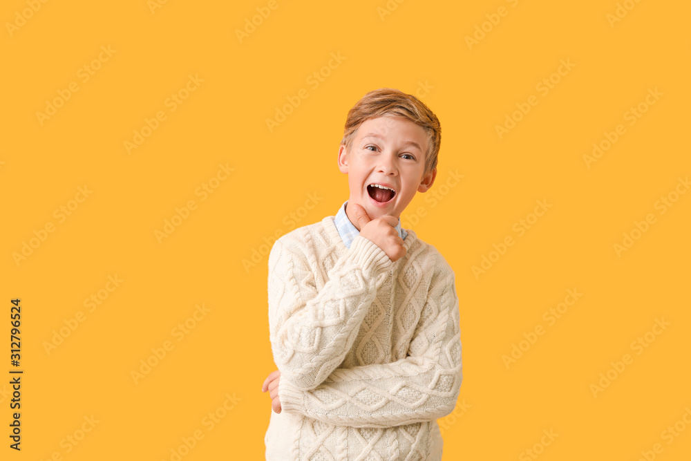 Cute little boy in autumn clothes on color background