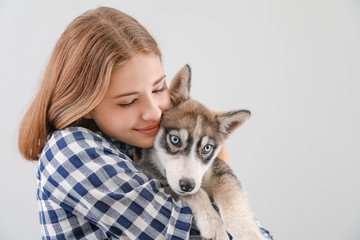 Canvas Print - Cute teenage girl with funny husky puppy on light background