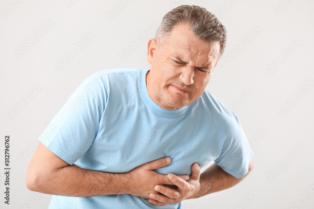 Mature man suffering from heart attack on white background