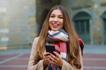 Wall Mural - Happy cheerful girl messaging with smart phone app looking at ca