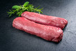 Raw dry aged venison tenderloin fillet steak natural with herbs offered as closeup on a modern design board