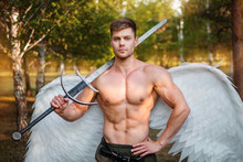 A Young Angel, A Bodybuilder In Plate Armor On His Legs With Wings Behind His Back, Holds In His Hands A Two-handed Sword.