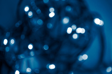 Blurred festive lights backgound. Bokeh of lights on blue background. 2020 color trend.