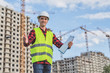 © vadimalekcandr - civil engineer in white helmets and a yellow vest on the background of the house under construction.