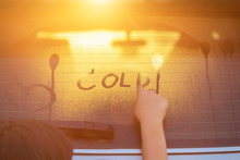 Children Writing Word "COLD" On Wet Rear Mirror Of Her Father SUV Car