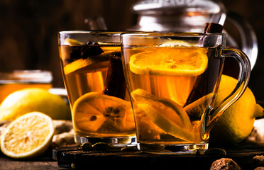 Canvas Print - Hot healing tea with ginger, honey, lemon and spices in glass cup, rustic wooden background copy space