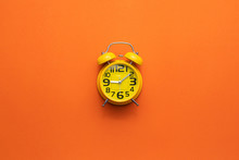 Yellow Alarm Clock On The Middle Of Orange Background