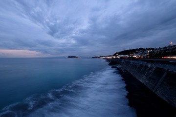 Wall Mural - evening of coastline in Kamakura Japan. Sea waves against coast. Cloudy sunset sky. Wide angle and long exposure