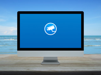 cctv camera flat icon on desktop modern computer monitor screen on wooden table over tropical sea and blue sky with white clouds, Business security and safety online concept