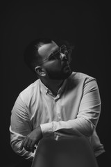 Portrait of bearded man in sunglasses and white shirt smoking on black background. Vaping man.