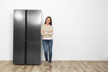 Sticker - Happy young woman near refrigerator indoors, space for text