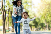 Young Cute Happy Little Asian Toddler Girl Running In Park With Mother. Mom Taking Care Daughter By Following And Hold Child Carefully. Kid Smiling Enjoy Learning To Walk And Run, Family Relation.