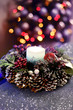New Year Christmas wreath with cones and a burning candle on a background of sparkling holiday bokeh. Christmas New Year decorations in the homely atmosphere of a cozy winter evening.
