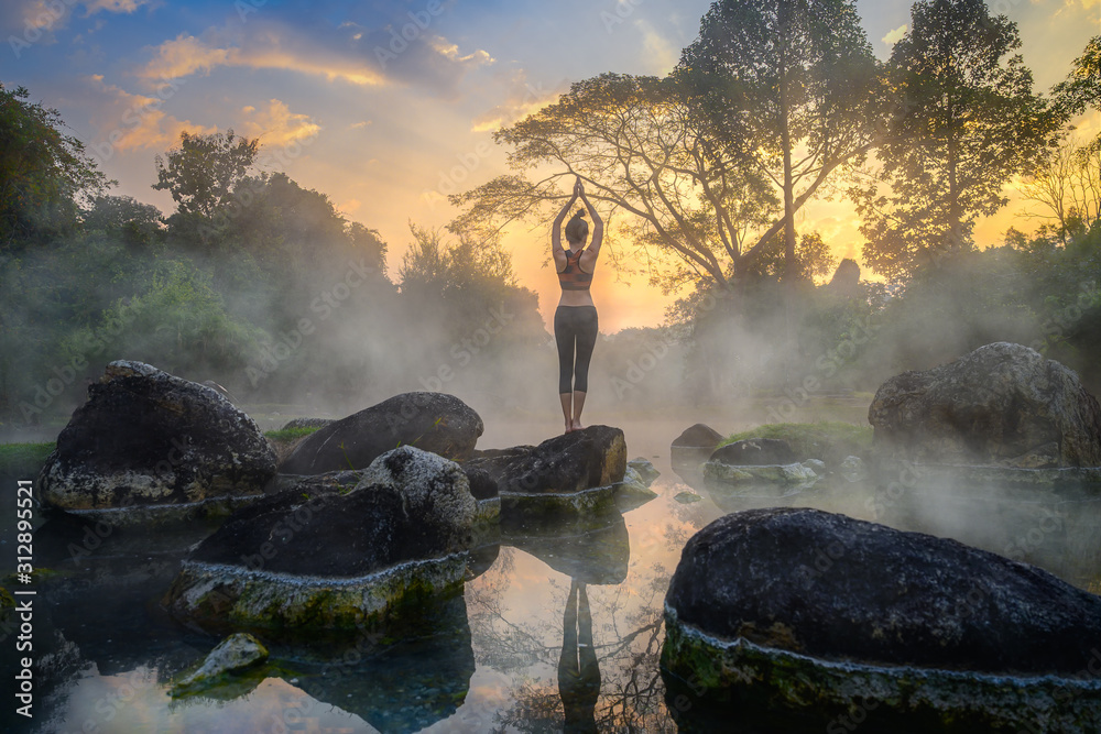 young woman in action of yoga practice in steaming hot spring water, the nature yoga exercise in hot spring steaming water at morning sunrise - obrazy, fototapety, plakaty 