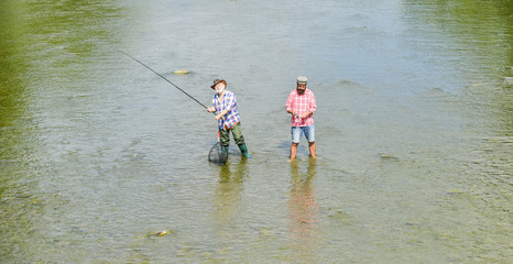 Wall Mural - one team. father and son fishing. adventures. recreation and leisure outdoor. hobby and sport activity. Trout bait. two happy fisherman with fishing rod and net. Big game fishing. male friendship