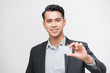 © makistock - Happy Asian man smiling and holding card on white background.