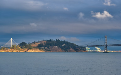 Fototapete - Bay Bridge Past Treasure Island in Afternoon LIght on Stormy Day