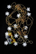 A small gift among golden beads and white wooden snowflakes on a black sparkling background. Holiday decorations.