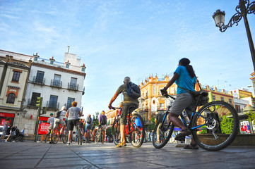 tourists on bike tour through triana neighborhood in seville, andalusia, spain