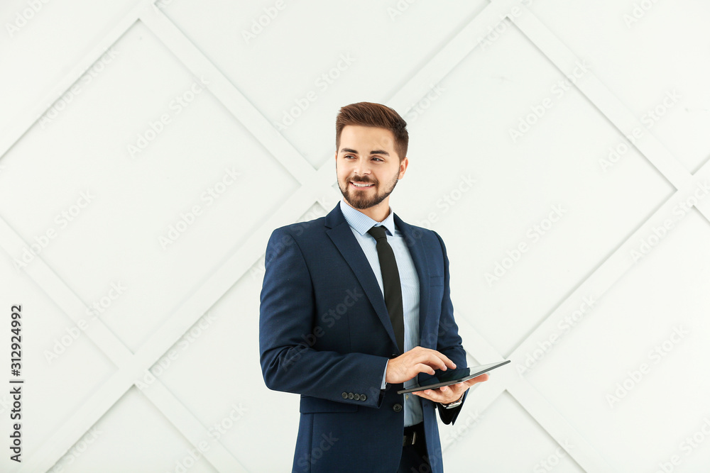 Portrait of handsome businessman with tablet computer on grey background