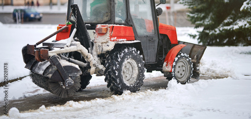 Fotografía Red tractor clearing snow on footpath, with snow plow and rotating brush