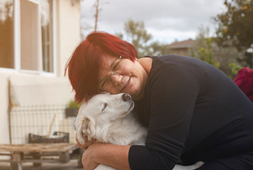 Mature woman embracing pet dog in nature