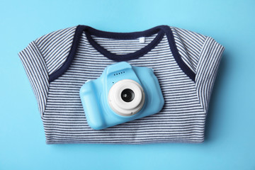 Wall Mural - Toy camera and children's shirt on light blue background, top view. Future photographer