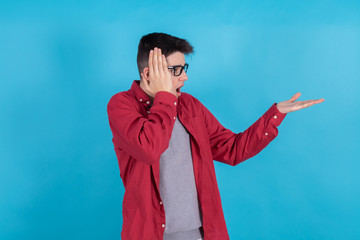 Wall Mural - young man or teenage student isolated on color background with the hand pointing amazed