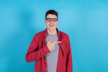 Wall Mural - young man or teenage student isolated on color background with the hand pointing to the side