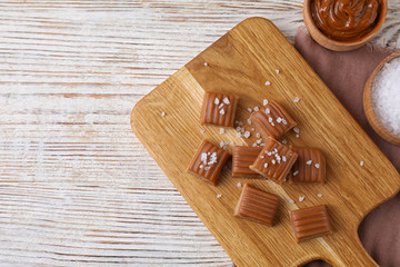 Delicious salted caramel on white wooden table, flat lay