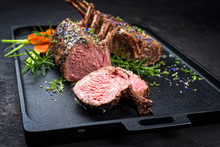 Barbecue Rack Of Lamb With Carrot And Herbs Offered As Closeup On A Modern Design Cast Iron Tray