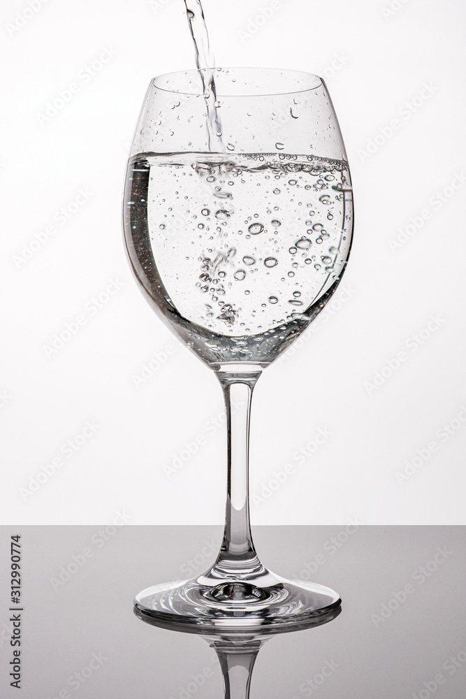 Pour water into clear glass. Drinking water pouring in wine glass. Splash  of water in glass