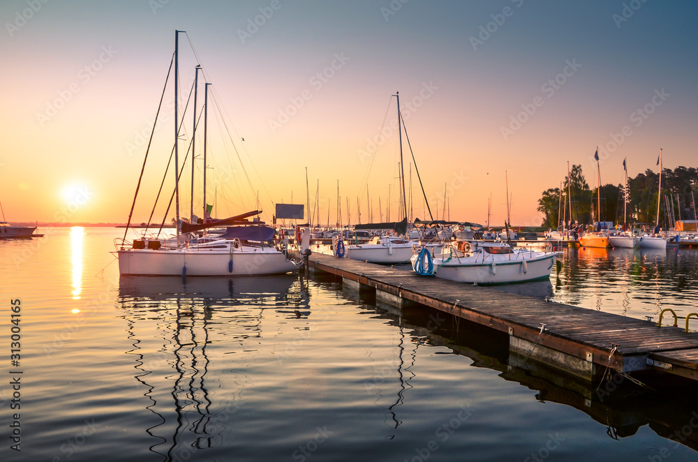 Boats docking in the marina at the Niegocin Lake during sunrise - Wilkasy, Masuria, Poland. - obrazy, fototapety, plakaty 