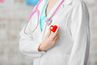 © Pixel-Shot - Female cardiologist with red heart on light background