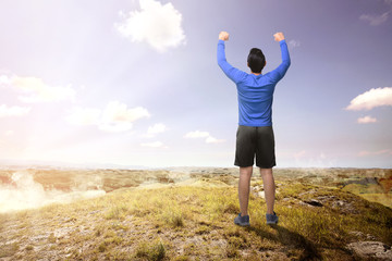 Poster - Rear view of Asian runner man with excited expression after a run on the hills