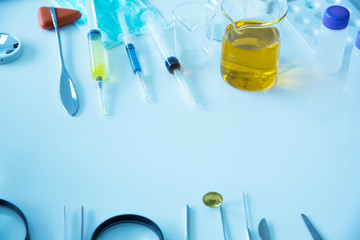 Syringes, medical instruments, and beaker, science laboratory with multicolored liquid on the laboratory table for chemical background