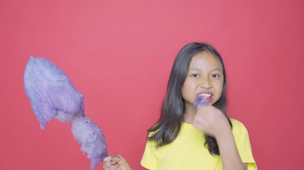 Wall Mural - Little girl enjoying a big cotton candy on studio