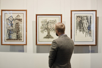 Rear view of young man in suit looking at modern art on the wall in museum