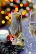 Glasses with champagne against the background of a Christmas tree in the lights. Very soft selective focus.