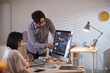 © AnnaStills - Businessman pointing at computer monitor with financial charts and explaining to employee who sitting at the table