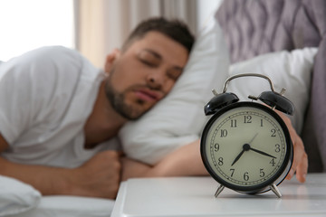 Canvas Print - Man sleeping at home in morning, focus on alarm clock