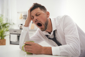 Sticker - Sleepy man with cup of drink at home in morning