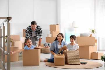 Canvas Print - Happy family having fun while unpacking moving boxes at their new home