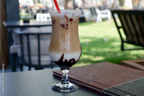 Download Iced Coffee Latte With A Red Tube On A Table With A Menu Sunny Day On A Blurred Background Green Grass And Cafe Tables And Chairs Stock Photo Adobe Stock