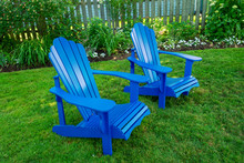Blue Adirondack Chairs In A Back Yard.