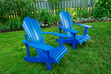 Blue Adirondack chairs in a back yard.