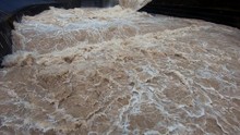 Slow Motion Close Up Dirty Brown Raging Turbulent Flood Water Leaving Dam And Spills In Man Made River Canal